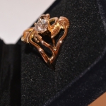 Voici une bague or rose vue de profile, faite d'un entrelacs de petites feuilles avec au centre de la canopée un diamant en solitaire.