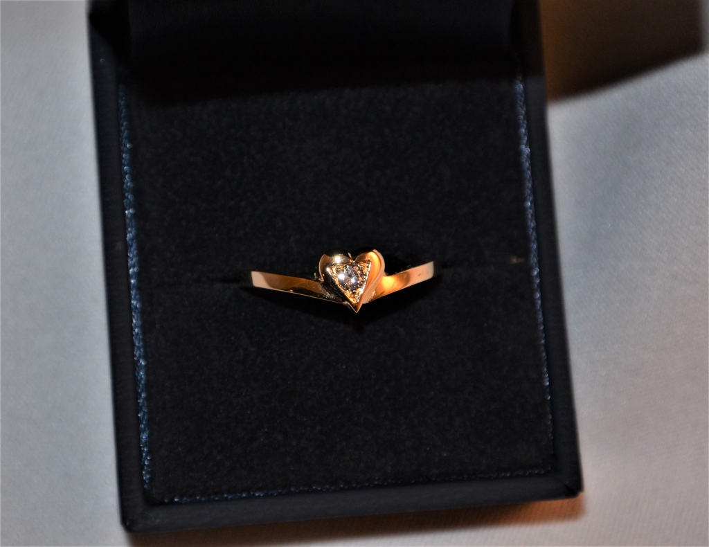 Voici une bague en or rose avec un petit cœur et en son centre un diamant sertit de trois grains.