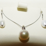 Une parure, boucles d'oreilles col de cygne et pendentif, les perles sont montées avec de l'or blanc.