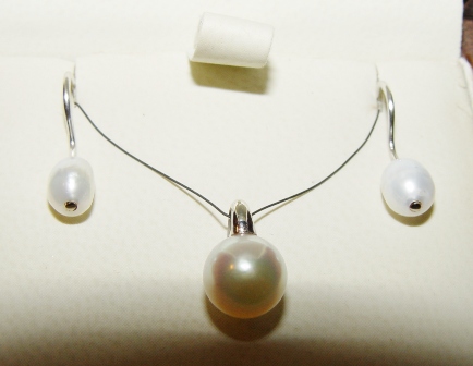 Une parure, boucles d'oreilles col de cygne et pendentif, les perles sont montées avec de l'or blanc.