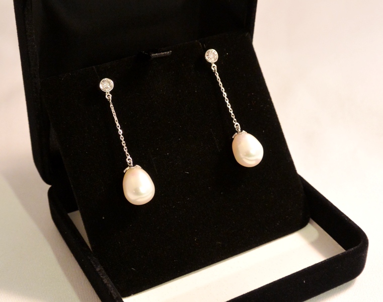 Voici une paire de boucles d'oreilles or blanc, diamants et perles.