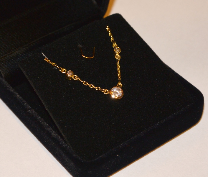 Voici un collier en or jaune à trois diamants serti en serti clos.