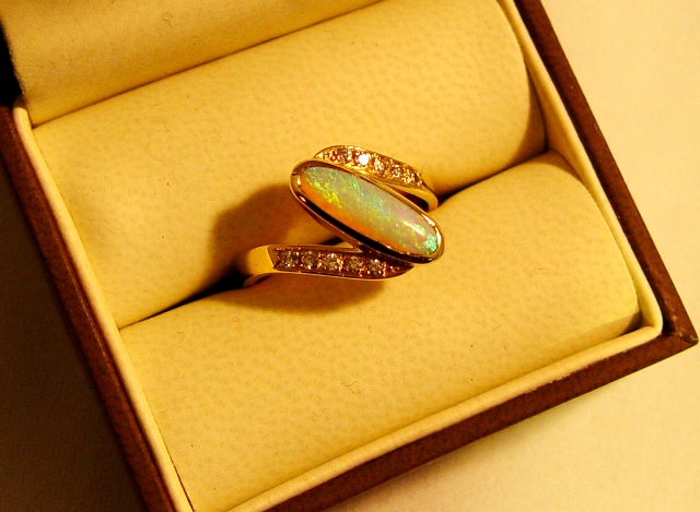 Bague or jaune avec une opale en solitaire épaulée de diamants. Pièce réalisée à partir d'anciens bijoux qui n'étaient plus appréciés.