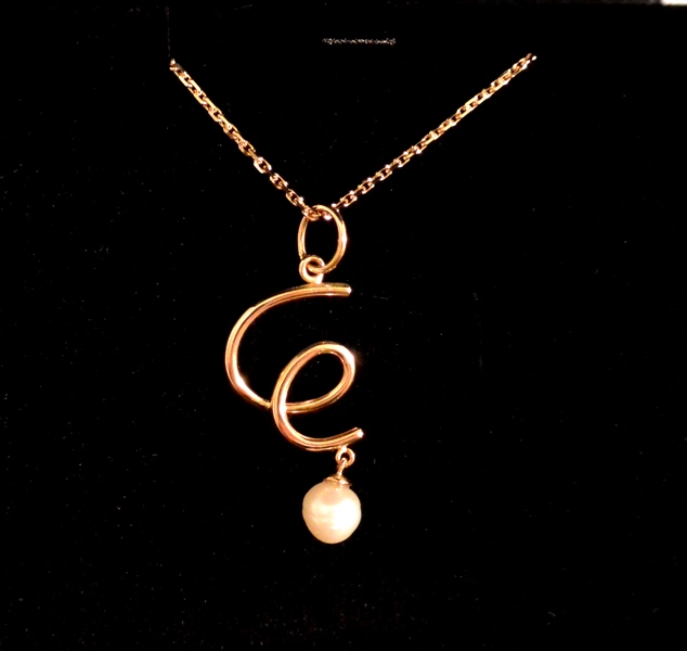 Voici un pendentif en or rose en forme de E façon @ avec une perle naturel récupéré dans une huitre par le client.