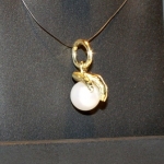 Main en or jaune posée sur une perle.