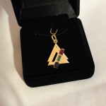 Ici nous avons le pendentif et la bague assortie. Tous deux en or jaune sertis d'un rubis, d'une émeraude et d'un saphir bleu.