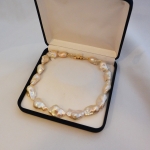 Voici une collier de perles baroques avec un mousqueton or jaune.