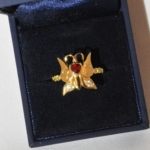 Voici une bague papillon en or jaune avec deux petit diamant dans les ailes, un rubis en forme de cœur au centre, gravée de deux initials et flanqué de deux petit symboles infini. l'or et les diamant on été récupéré sur une ancienne chevalière.