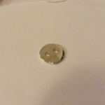 Un bouton en argent tout cabossé…
