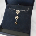 Voici un collier en argent où les 3 cercles forment le nom Maud, le symbole astrologique du lion remplaçant le A.