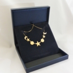 Voici un collier or jaune fait de petites étoiles, lunes et soleils gravés dans les cercles.