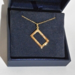 Voici un pendentif or jaune martelé, rectangulaire et serti de diamants.